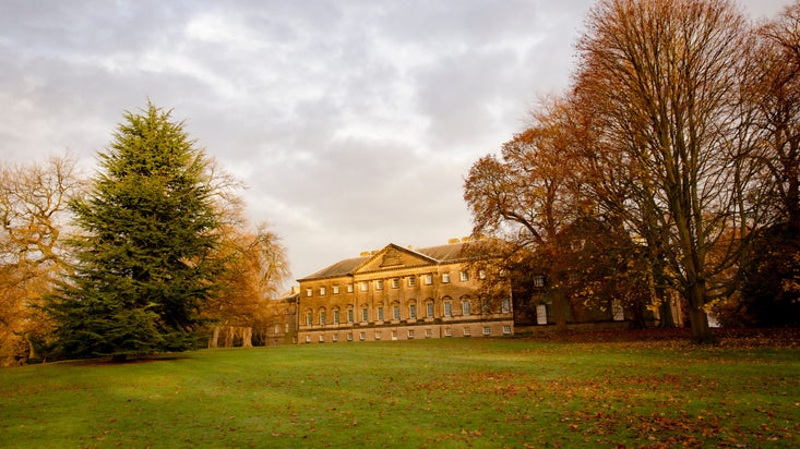 The exterior view of the house at Nostell with grey skies, wintery trees and a grass lawn in front.